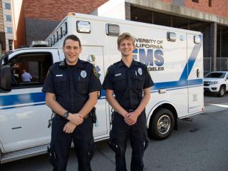 Two EMTs standing in front of an ambulance